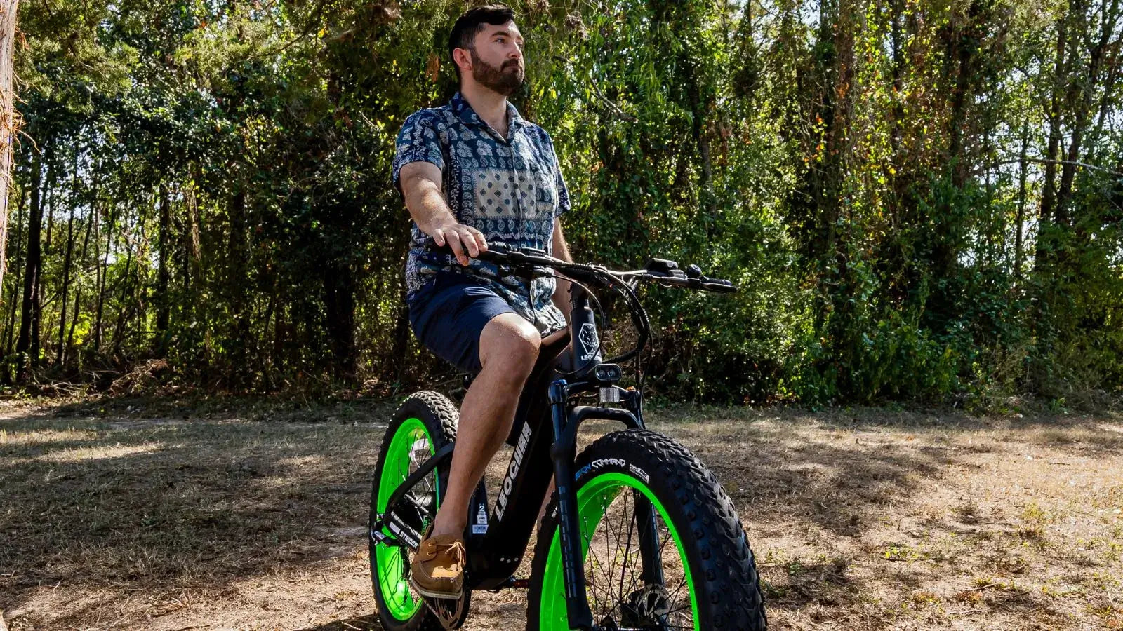 Man riding a no pedal electric bike for adults in a wooded park area