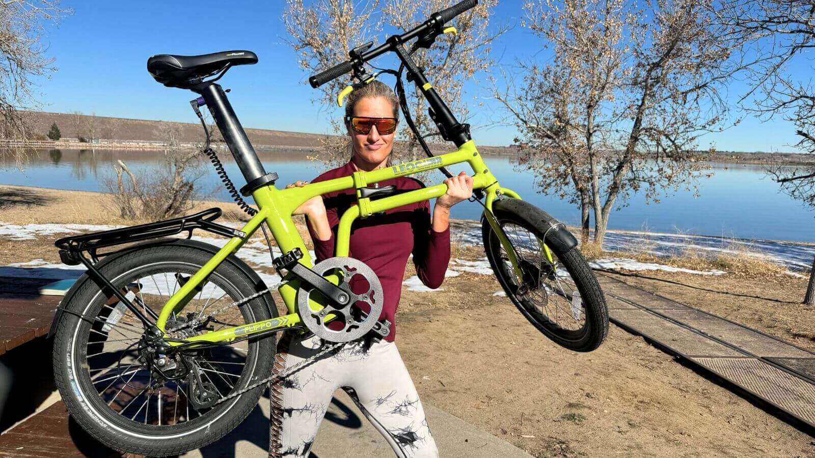 Woman lifting e-bike near trailer hitch setup