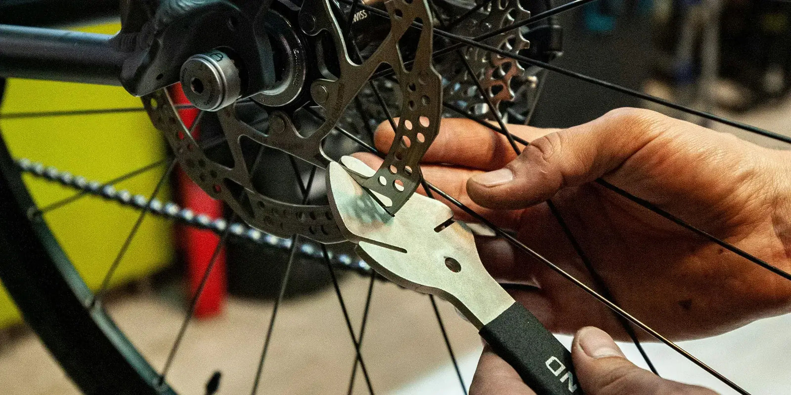 Mechanic adjusting the disc brake rotor on an electric bike wheel with a wrench tool