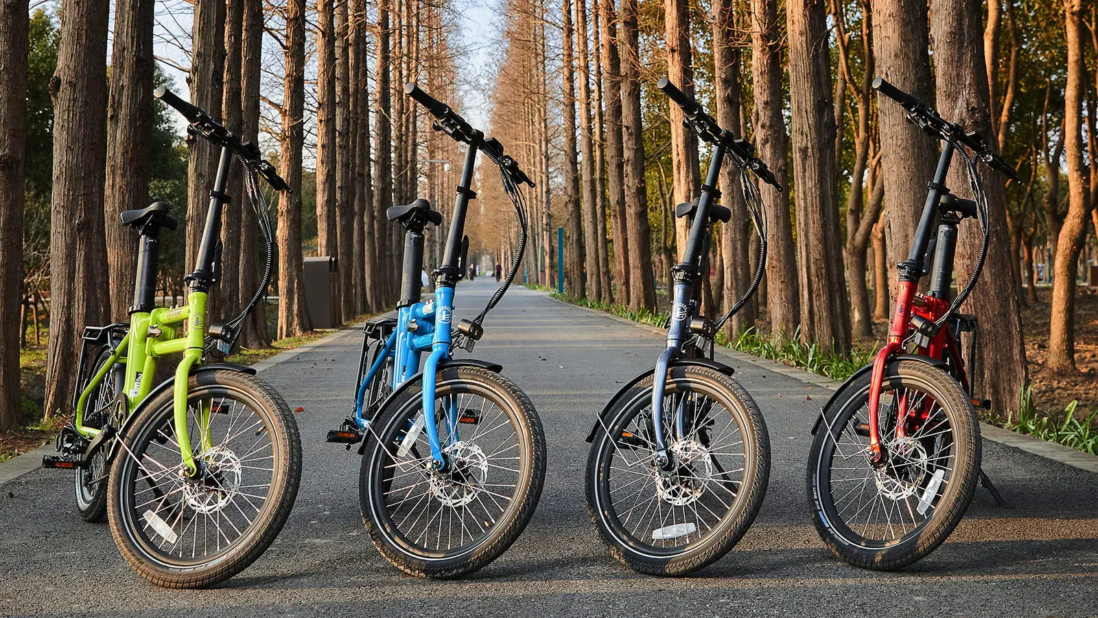 Leoguar Flippo folding e-bikes in multiple colors displayed on a tree-lined path.