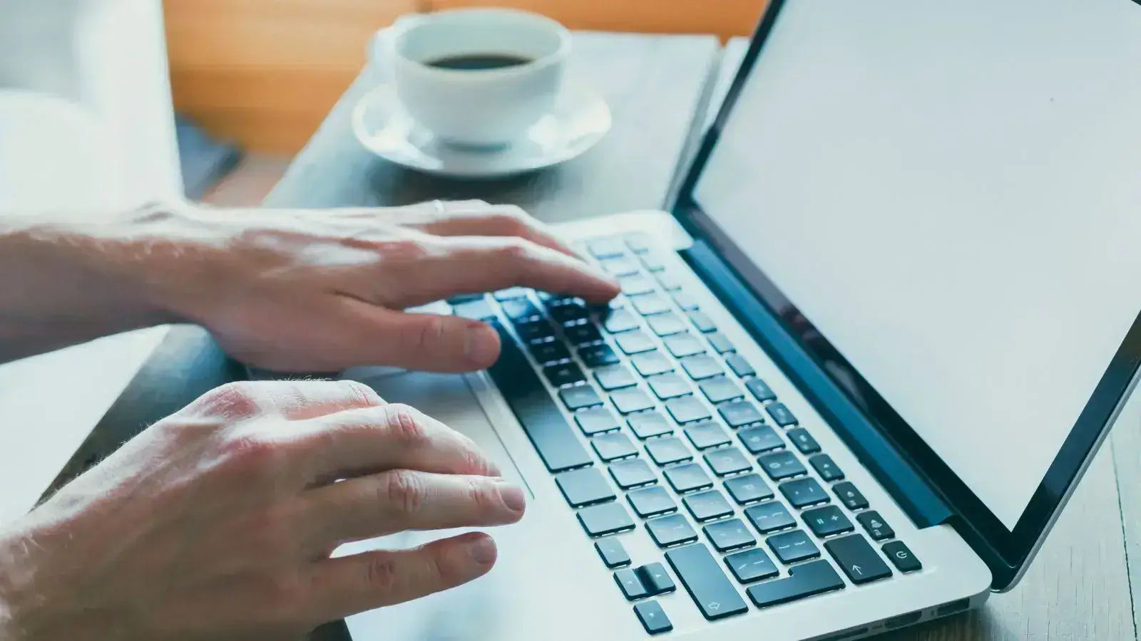 Person browsing online deals for electric bikes on a laptop with coffee nearby