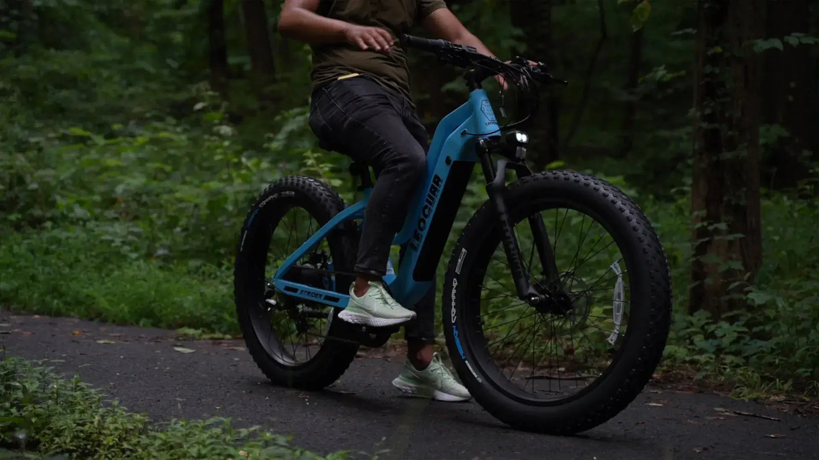 Person riding an electric bike with pedals on a forest trail