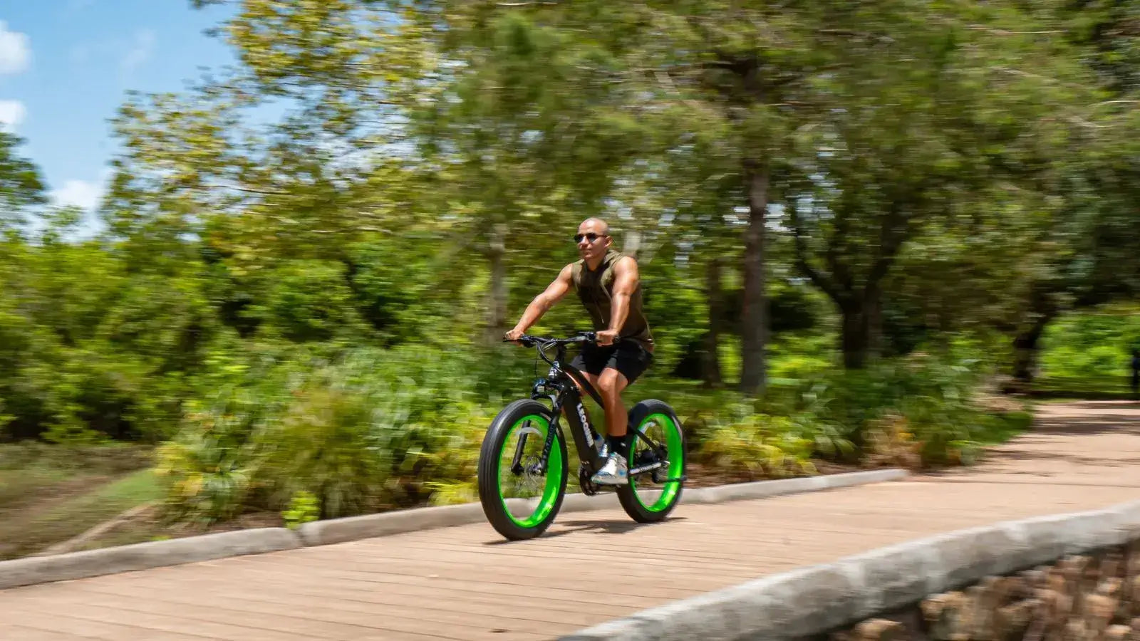Man riding a high-speed electric bike on a wooden path surrounded by greenery