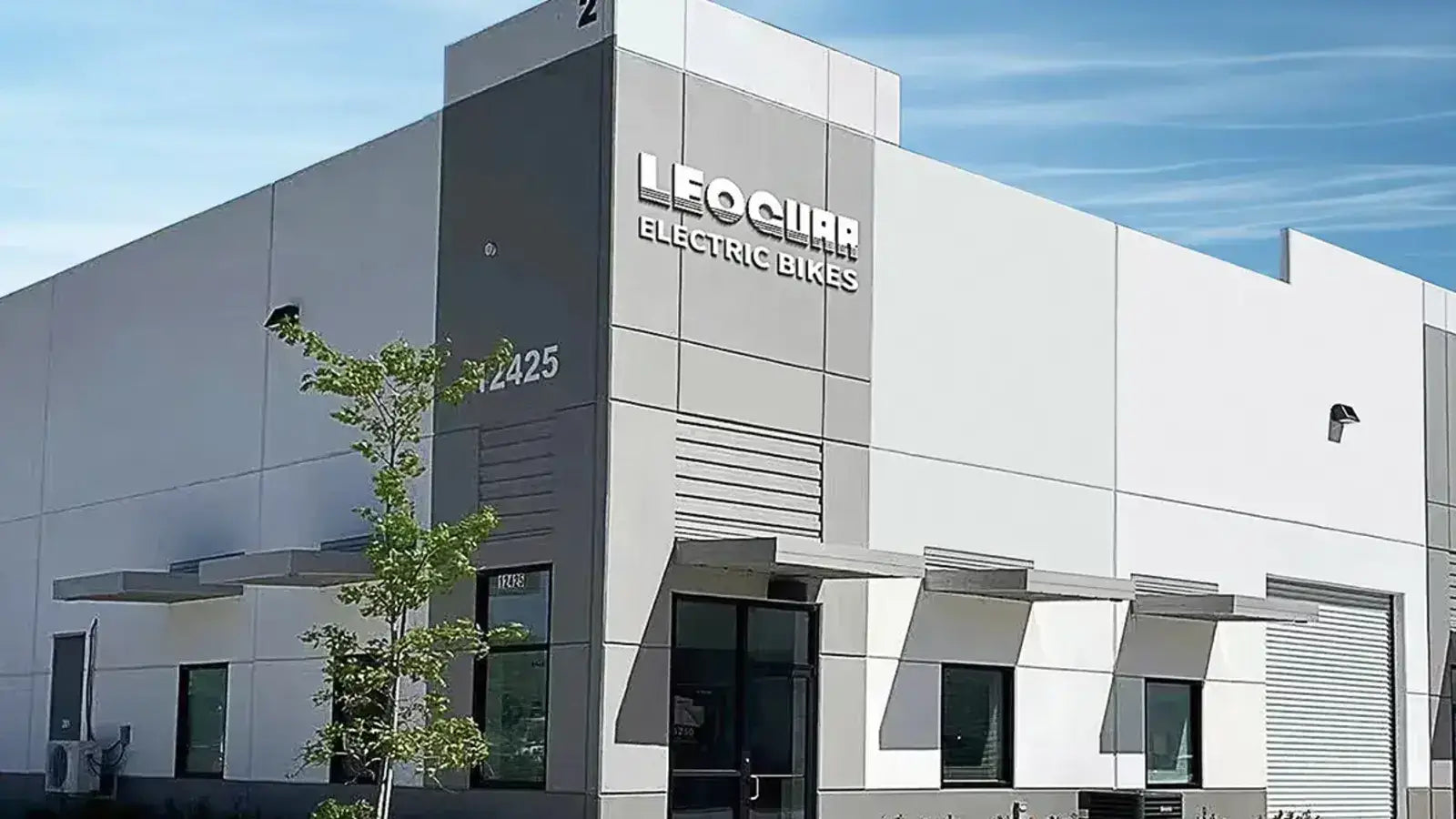 Modern electric bicycle company headquarters building exterior with clean white facade under blue sky