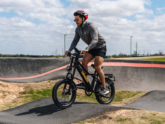 Man riding the Sprint Fat Tire Utility Ebike on a pump track under a cloudy sky