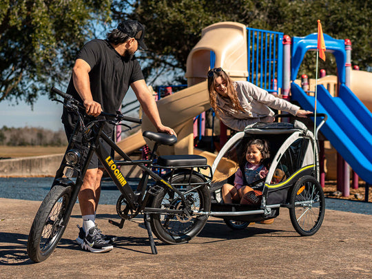 Family with a Leoguar Utiity e-bike and child trailer at a playground.
