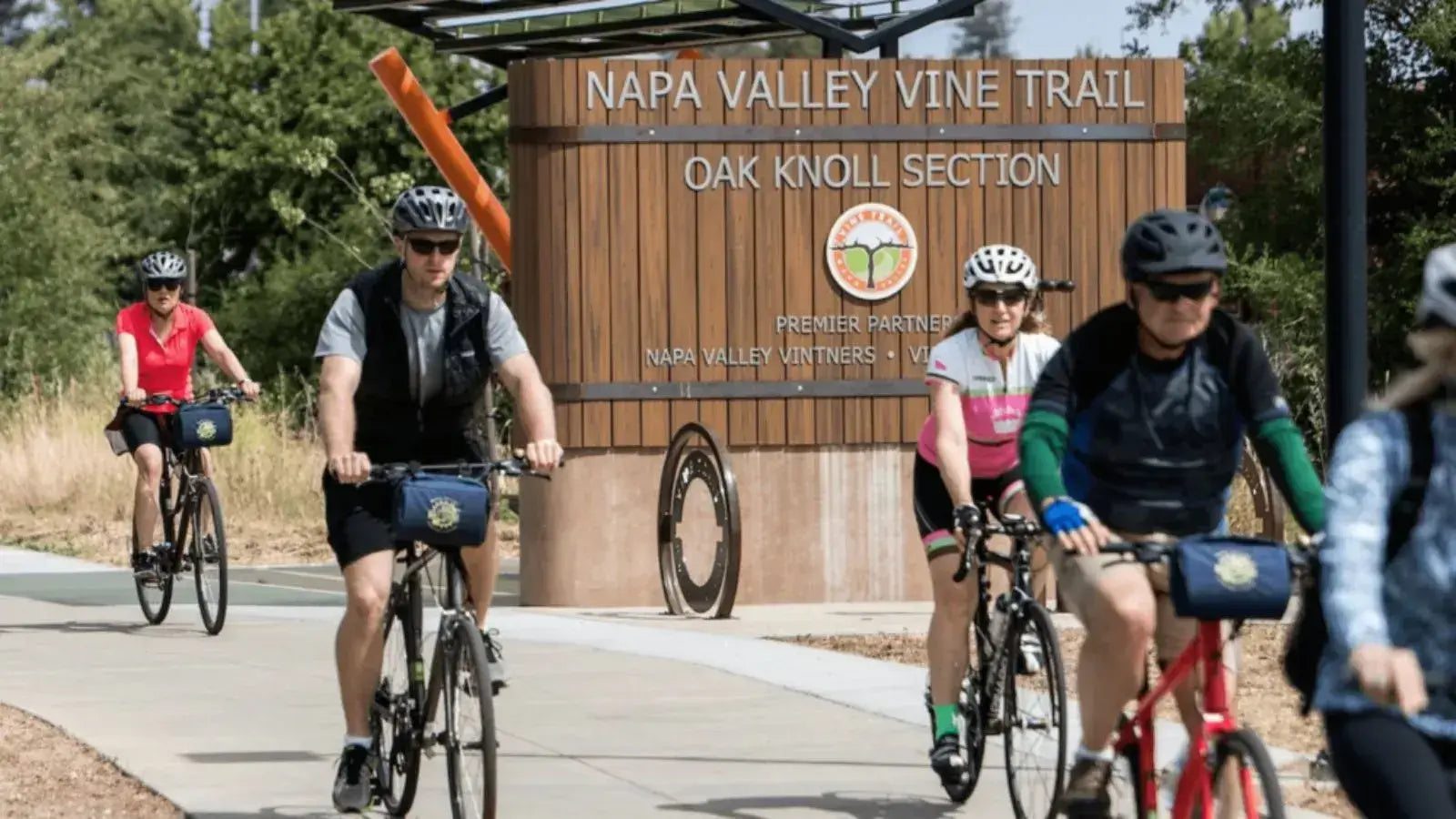 Cyclists riding various types of electric bikes on a public trail, highlighting diversity in e-bike quality and design.