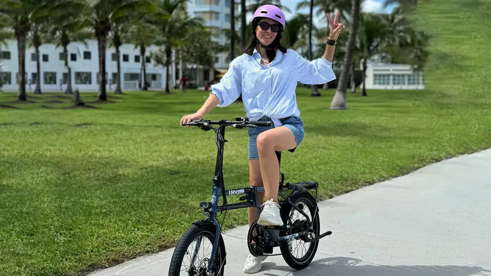 Woman riding a folding electric bike on a sunny pathway, demonstrating casual street-legal e-bike use