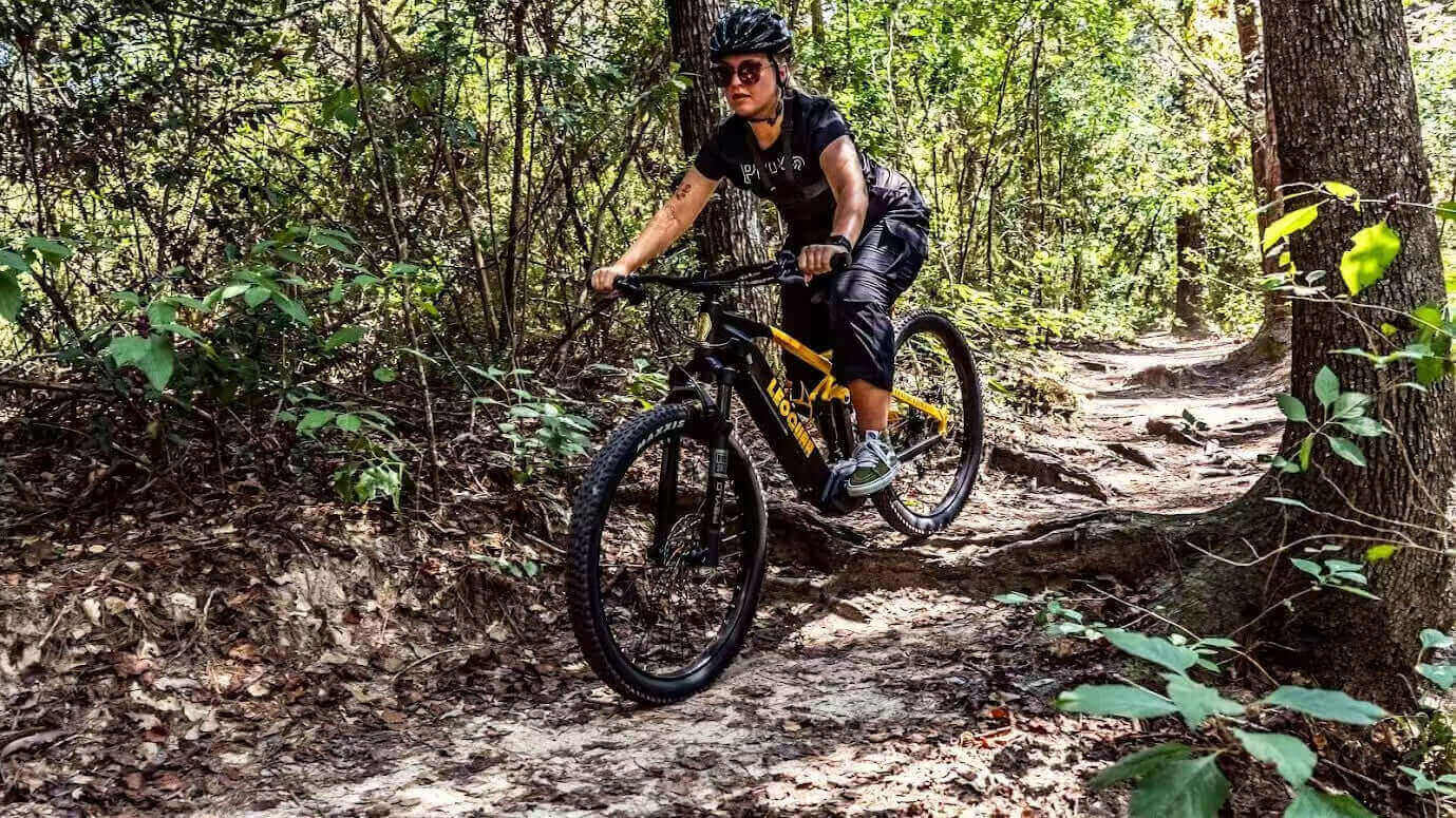 Rider exploring forest trail with a full suspension electric mountain bike
