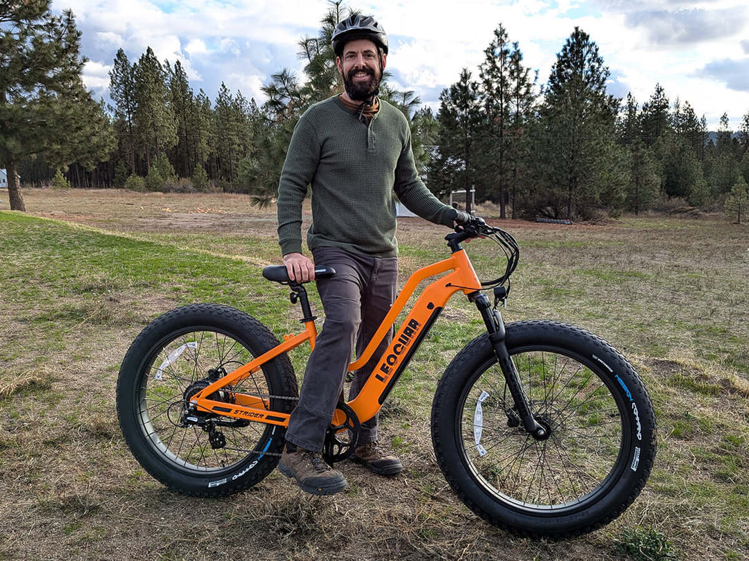Outdoor shot of rider climbing rough terrain on orange Fastron ST e-bike