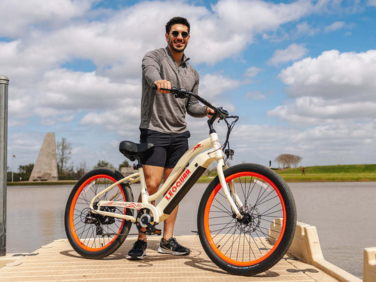 Man standing on dock with beige Zephyr ST cruiser ebike, lake in background