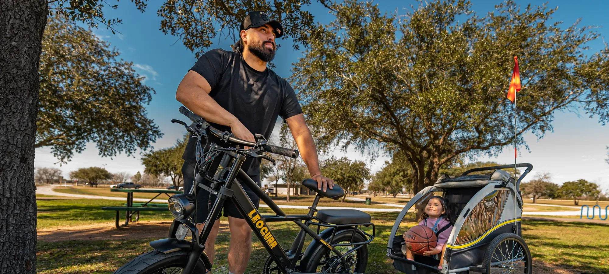 Man with Leoguar fat tire electric bike and kids trailer in park
